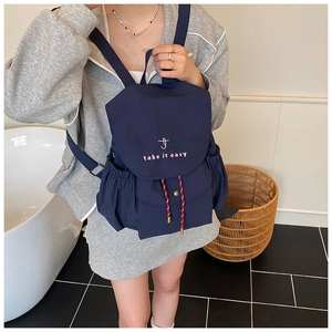 Detail of navy blue canvas backpack with 'take it easy' embroidery and drawstring pockets