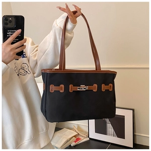 Macro detail of canvas tote featuring leather trim and iconic metal turn-lock closure
