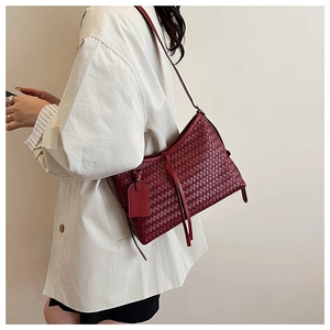 Detailed macro shot of the dark red woven leather texture and elegant tassels on a bucket bag