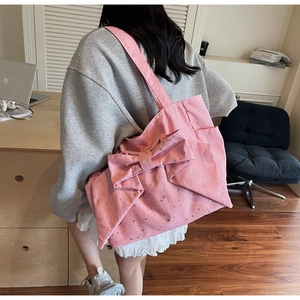 Pink bow canvas tote bag with star patterns shown from back on a shoulder