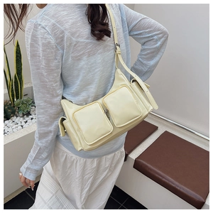 Detailed view of cream leather crossbody bag with multiple pockets worn by a model