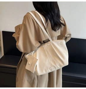 Détail du grand sac cabas beige avec design plissé et mini pochette assortie sur la bandoulière