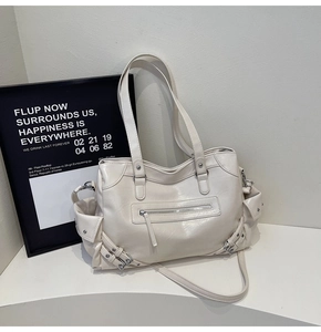 Close-up of white biker tote bag showing silver rivets and detailed front zipper pockets