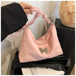 Detail of pink suede tote bag featuring silver butterfly charm and knotted rope handle