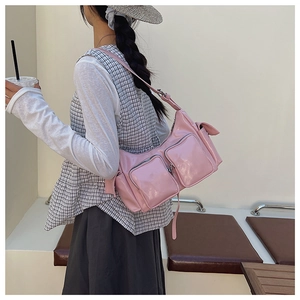Detail showing pink patent leather shoulder bag with pockets worn by a model