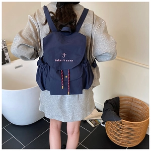 Détail d'un sac à dos bleu foncé avec broderie rose et cordons de serrage décoratifs