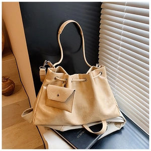 Gros plan du sac seau plissé beige avec mini pochette assortie et texture en similicuir