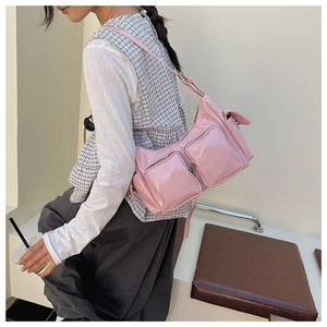 Detail view of pink patent leather crossbody bag with multiple functional zipper pockets