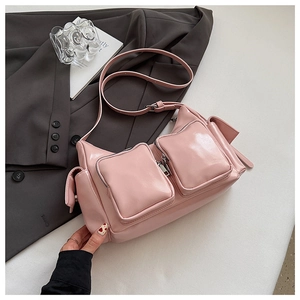 Detail of pink glossy patent leather shoulder bag with functional zipper pockets