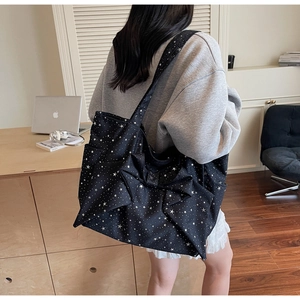 Detail of black canvas tote bag featuring large white stars and a decorative bow