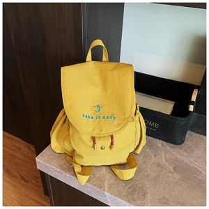 Detail of yellow canvas backpack showing the embroidered slogan and colorful drawstring