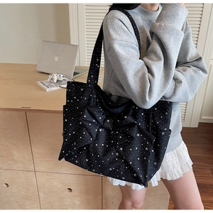Detail of black canvas tote bag featuring white star pattern and large bow decoration