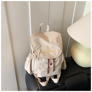 Detail of beige canvas backpack with take it easy yellow embroidery and drawstring pocket