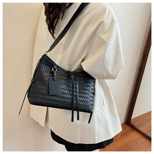 Detail of woven hobo shoulder bag featuring leather tassels and premium texture