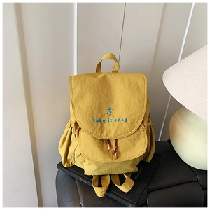 Close-up of bright yellow canvas backpack featuring 'take it easy' embroidery and drawstring