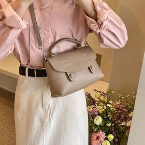Borsa a tracolla in pelle taupe con patta e manico in metallo indossata da modella
