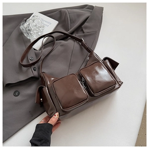 Detail shot of a dark brown glossy leather shoulder bag with vintage utility pockets