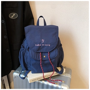 Navy blue nylon backpack detail with red drawstring and 'take it easy' embroidery