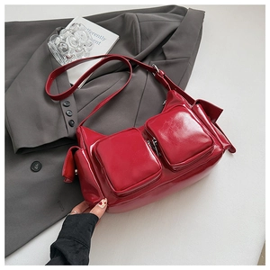Close-up of glossy red patent leather shoulder bag with textured pocket details