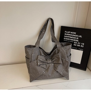 Detail of star pattern canvas tote bag with bow accent on white marble surface