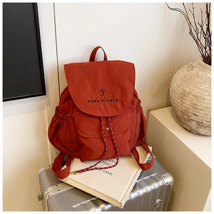 Detail of brick red drawstring canvas backpack with embroidered J and take it easy text