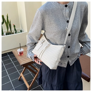 Detail of white woven leather hobo bag with a slim strap worn by a model outdoors