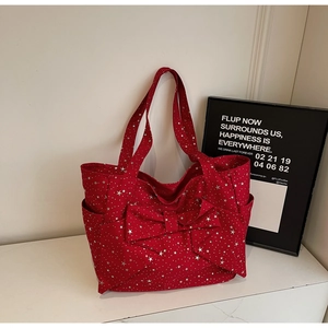 Detail view of red canvas tote with silver star prints and large decorative bow knot
