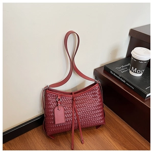 Detail of burgundy woven bucket bag showing premium texture and shoulder strap