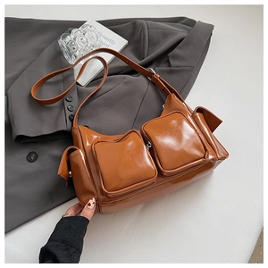 Detail view of glossy brown PU leather shoulder bag with multiple front zip pockets