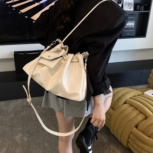 Sac seau plissé en cuir crème porté à l'épaule dans un intérieur au design moderne