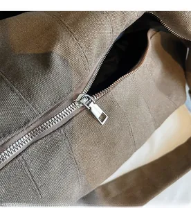 Close-up of durable canvas texture and smooth silver metal zipper on brown hobo bag