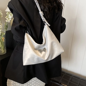 Minimalist beige shoulder tote bag with silver butterfly pendant shown on model