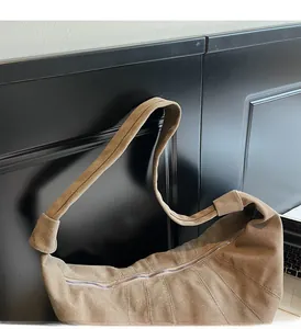 Detail of brown canvas dumpling bag featuring wide shoulder strap and metal zipper