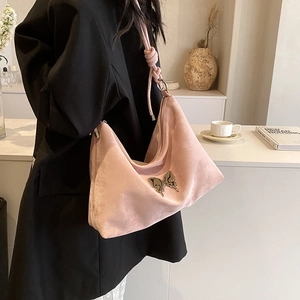 Pink velvet tote bag with silver butterfly accent shown as a stylish shoulder bag for women