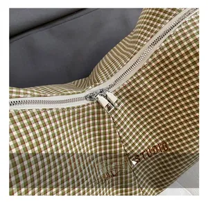 Detail of silver dual metal zippers and green checkered fabric on the MDL shoulder bag