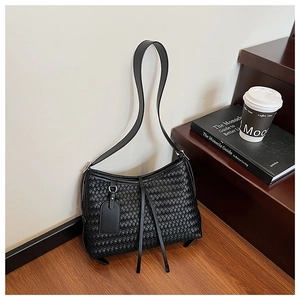 Detail of black woven hobo bag with checkerboard pattern on a wooden staircase