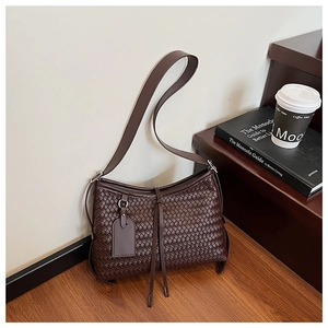 Detail of dark brown woven shoulder bag with delicate fringe and premium leather texture