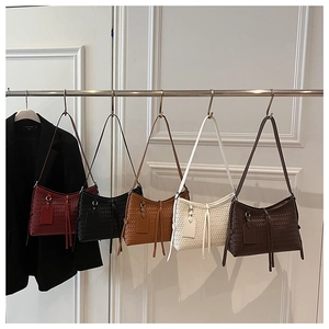 Detailed view of woven shoulder bags in five colors with leather tassels and straps