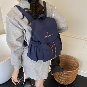 Navy canvas drawstring backpack with pink embroidery in a modern home lifestyle setting