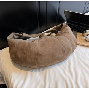 Detail of a brown canvas croissant bag with textured fabric and visible stitching
