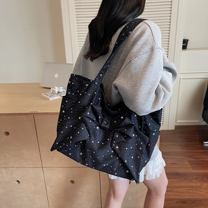 Black canvas tote bag with white star print and oversized decorative side bow