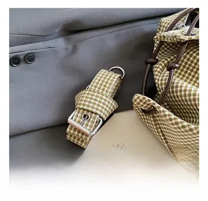 Detail of adjustable green checkered shoulder strap with silver buckle and metal hook