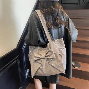 Grey canvas tote bag with bow detail and star print worn by model on stairs