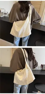 Détails de la texture plissée et de la bandoulière à bouton du sac cabas blanc crème