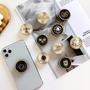 Foldable metal pop socket with rhinestones and flower designs on a light blue phone