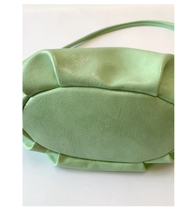Detailed view of the mint green dumpling bag showing pleated texture and oval bottom base
