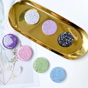 Starry sequin folding phone socket stand in multiple colors on a golden metal tray