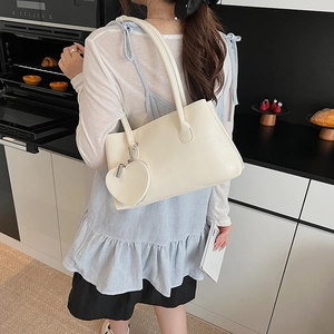 Borsa sottobraccio bianco crema con ciondolo a cuore portata a spalla