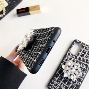 Détail d'une coque de téléphone noire à carreaux avec support à fleurs en strass