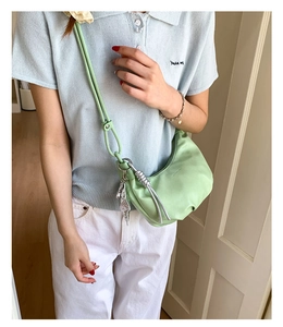 Detail of light green pleated dumpling bag featuring a silver leaf pendant and soft texture